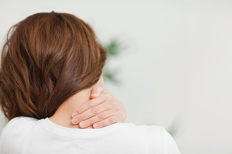 Woman in pain with hand on neck