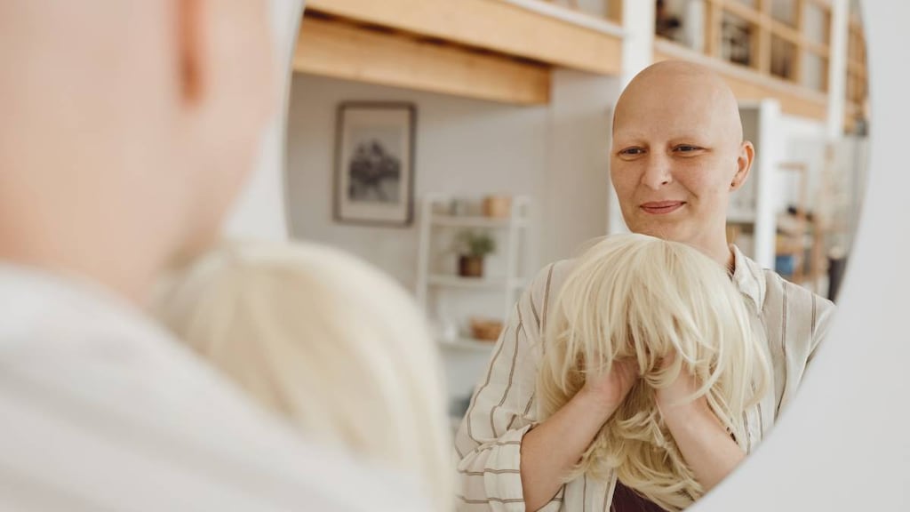 Chemotherapy patient with hair loss putting on a wig.