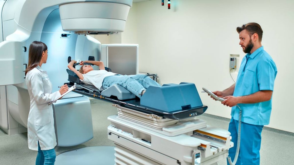 Woman on linear accelerator receiving radiation therapy for cancer. Doctor and technician working.