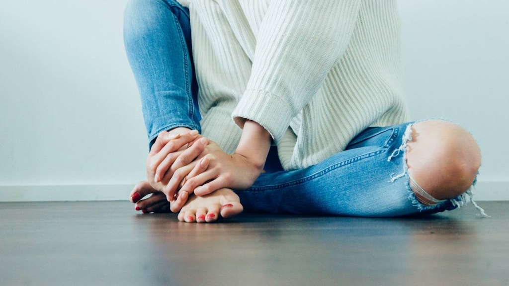 Woman holding sore hands and feet.