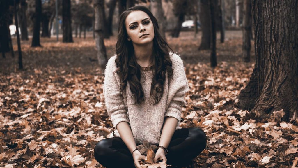 Depressed woman sitting in leaves