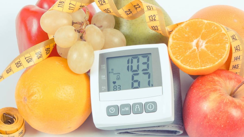 Blood pressure monitor with result of measurement, fresh fruits with vegetables and tape measure.image