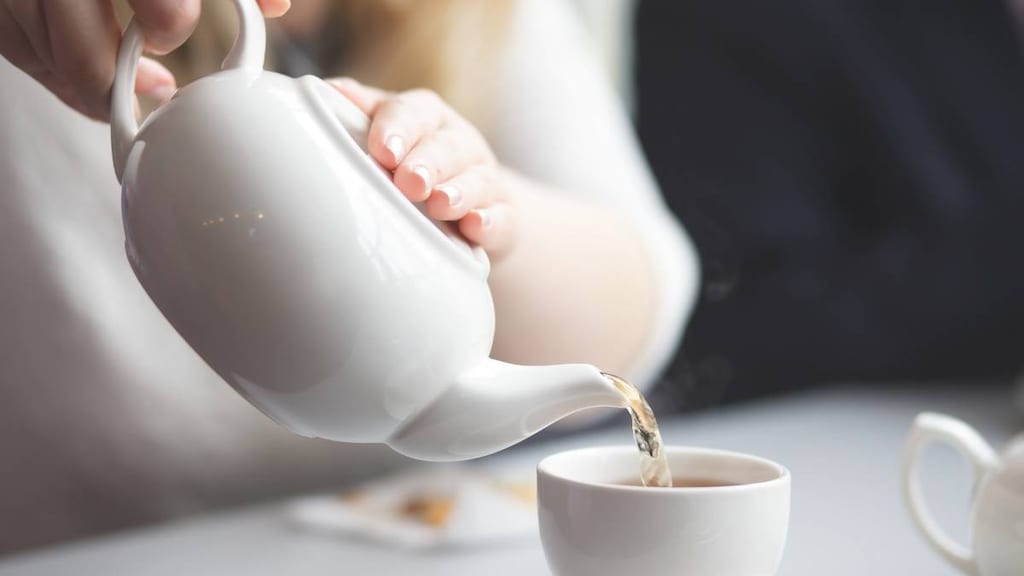 side view of a female pouring tea from a tea pot