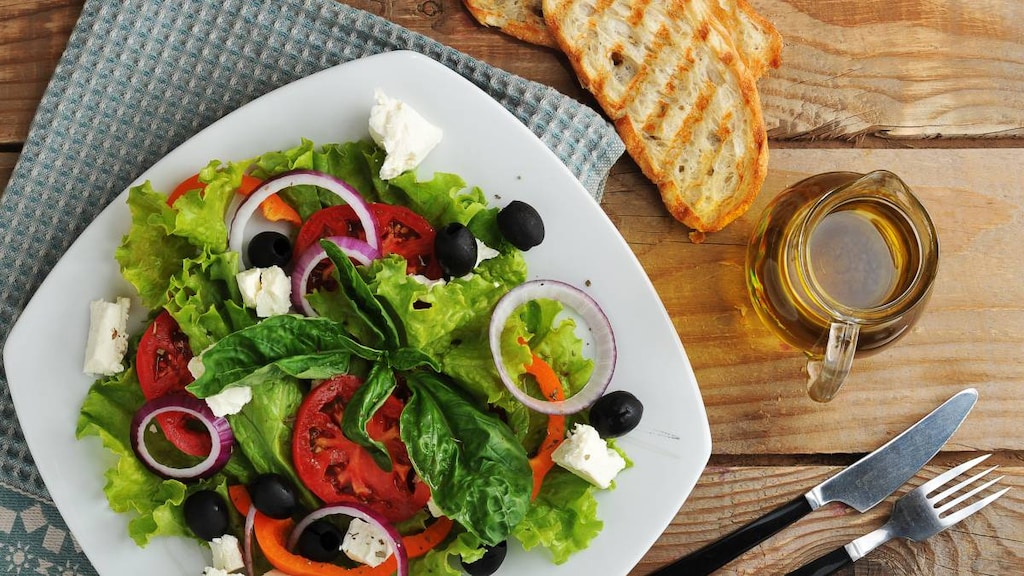 Salad with feta cheese, olives, tomatoes, lettuce and basil with olive oil.