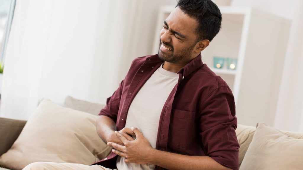 man with hands on stomach with pain