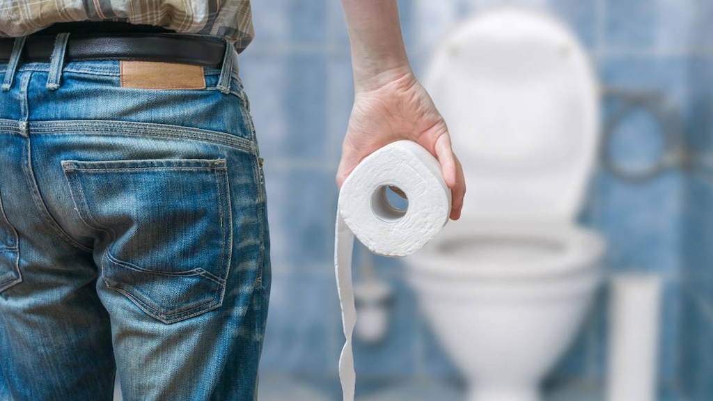 Man walking towards toilet with toilet paper