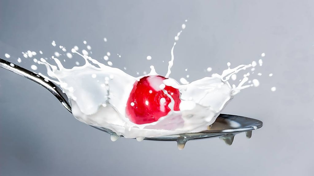 Milk containing lactose splashing on a spoon