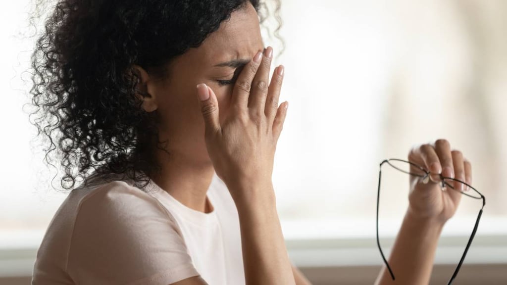 Woman with hand on eyes to stop twitching