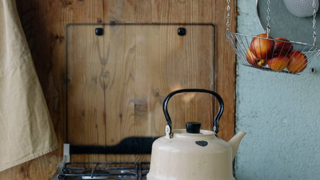 white ceramic teapot on stove top with timber background. image