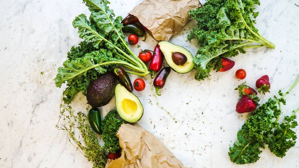 Lettuce, avocado and tomato spilling out of a brown bag and displayed on a table. image credit Wendy wei pexels.image