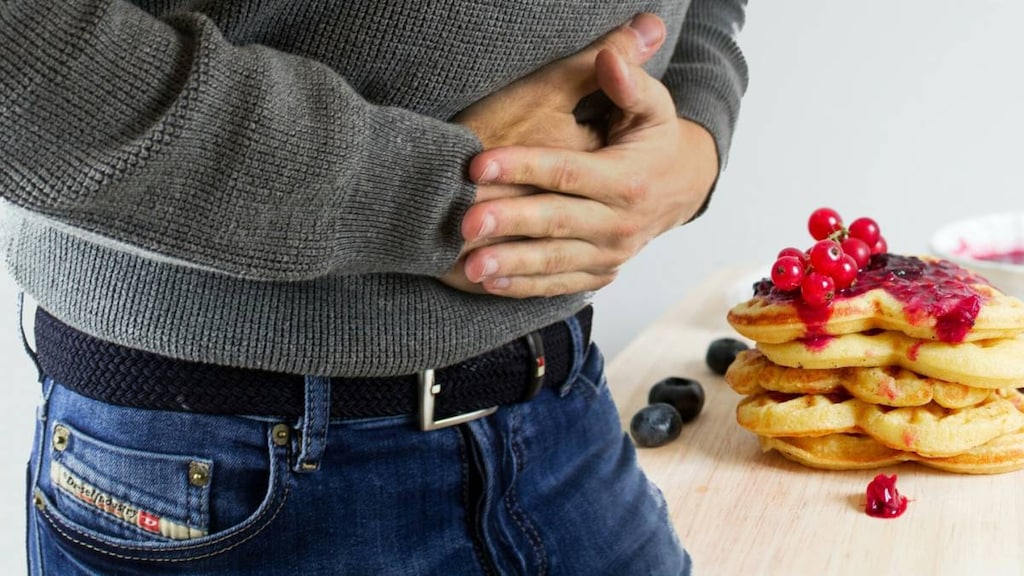 man with hands on stomach with pain