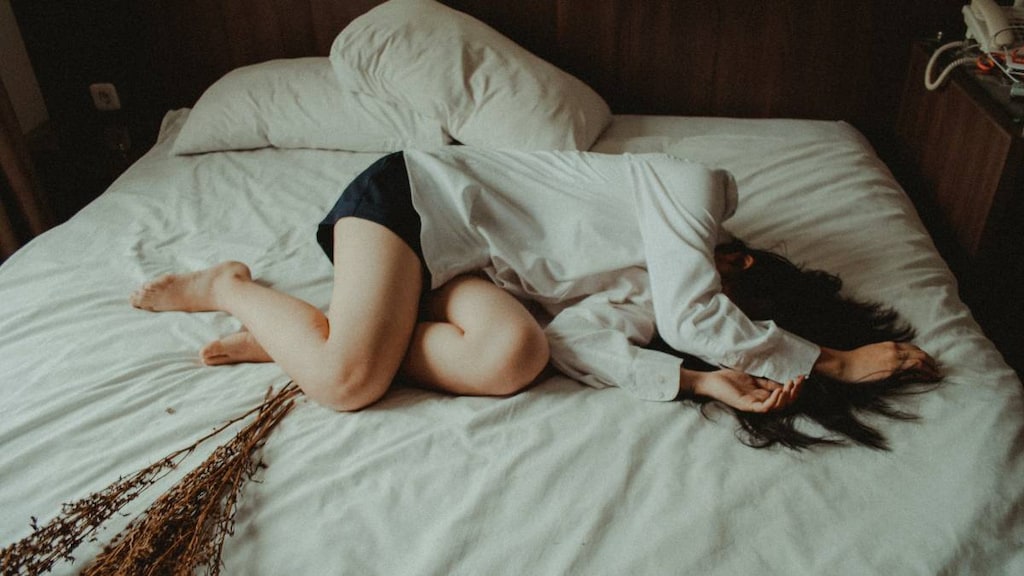 Women lying on bed feeling unwell.